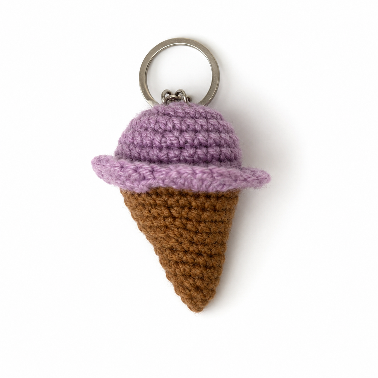 A crocheted ice cream cone keychain featuring a brown textured cone and a light purple scoop, attached to a silver metal key ring, shown on a plain white background.