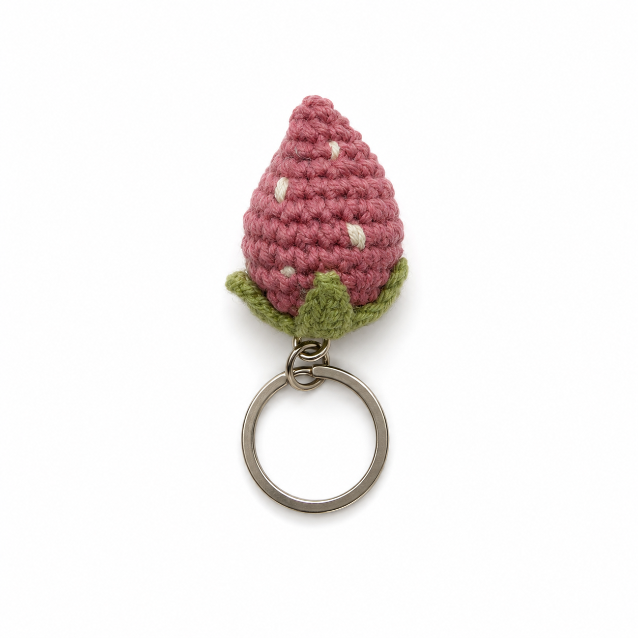 A crocheted strawberry keychain charm in dusty pink with white seeds and green leaves, attached to a silver metal split ring, shown on a plain white background.
